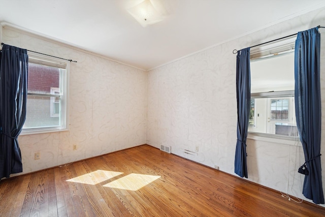 unfurnished room with visible vents, crown molding, and wood-type flooring