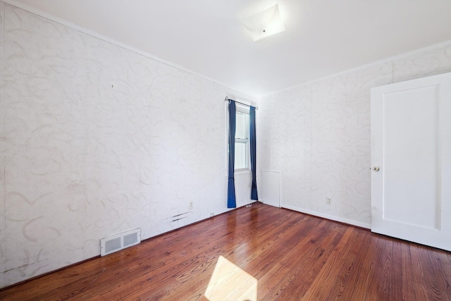 spare room featuring wood finished floors, visible vents, and ornamental molding