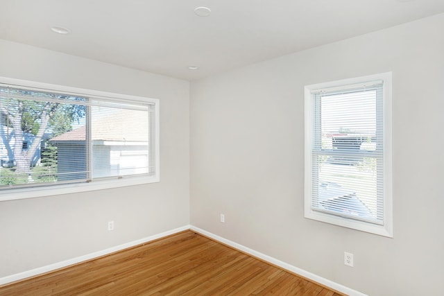 unfurnished room featuring light wood-type flooring, a healthy amount of sunlight, and baseboards