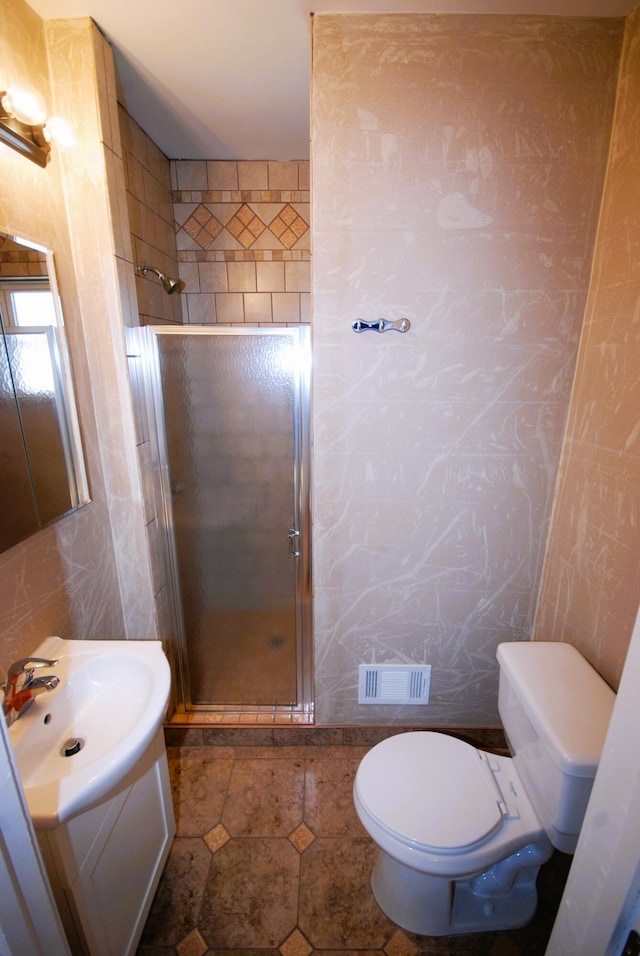 full bath featuring toilet, visible vents, vanity, tile walls, and a stall shower