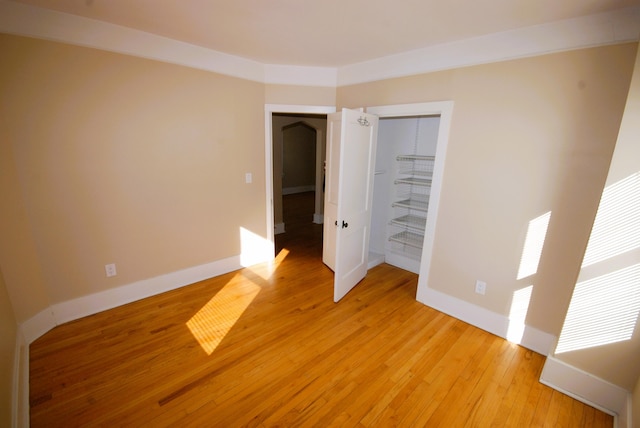 unfurnished bedroom with light wood-type flooring, baseboards, and a closet