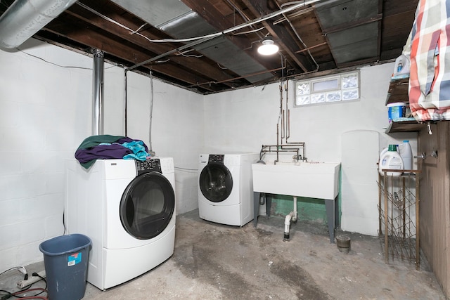 laundry room with concrete block wall, laundry area, a sink, and washing machine and clothes dryer