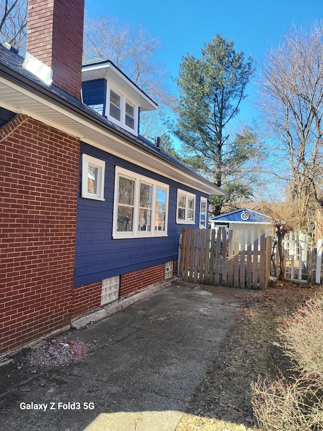 view of side of home with a chimney and fence