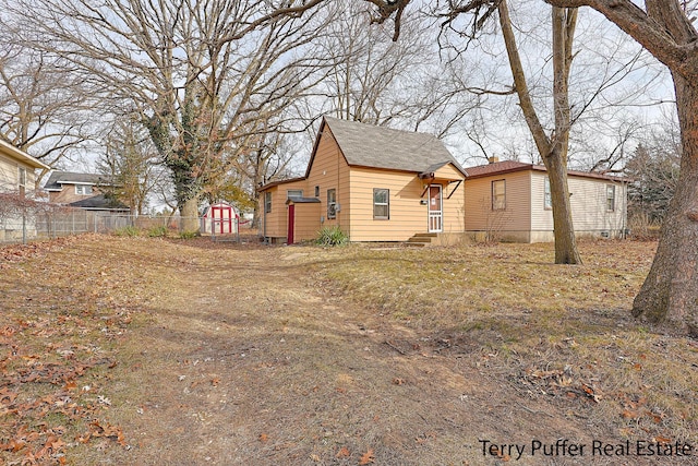 view of yard with an outbuilding, entry steps, a storage shed, and fence