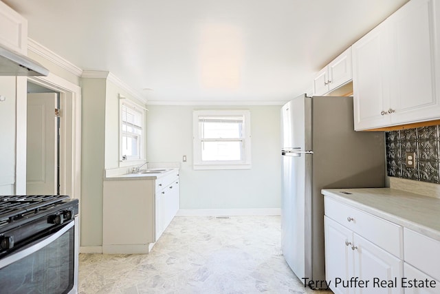 kitchen with ornamental molding, a sink, white cabinetry, stainless steel appliances, and light countertops