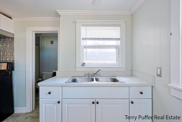 kitchen with visible vents, a sink, white cabinets, crown molding, and light countertops