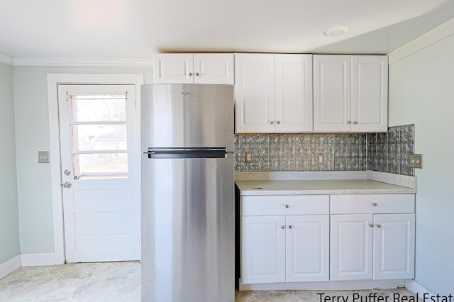 kitchen with light countertops, white cabinets, tasteful backsplash, and freestanding refrigerator