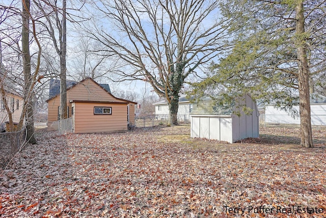 view of yard with a storage shed, an outdoor structure, and fence