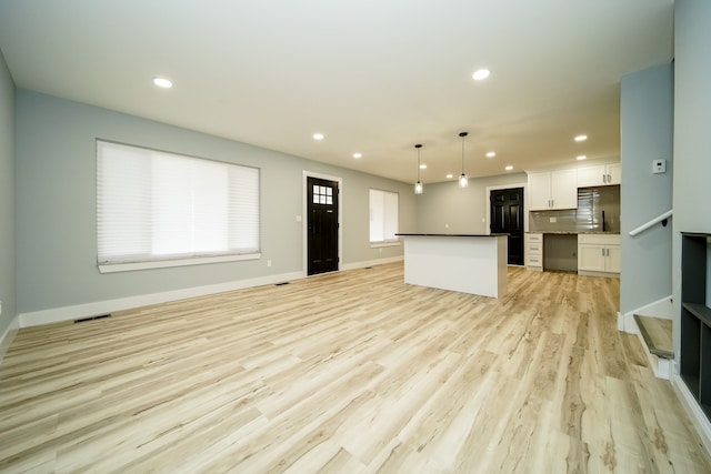 interior space with light wood finished floors, tasteful backsplash, recessed lighting, open floor plan, and white cabinetry