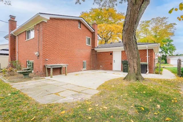 rear view of house with a patio, brick siding, a chimney, and a lawn