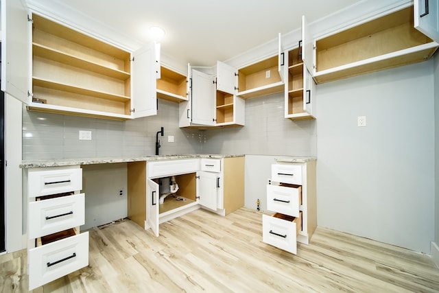 kitchen with light stone counters, light wood-style flooring, white cabinets, decorative backsplash, and open shelves