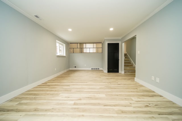 spare room with visible vents, baseboards, ornamental molding, stairway, and light wood-type flooring