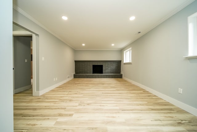 unfurnished living room with light wood finished floors, ornamental molding, a brick fireplace, and baseboards