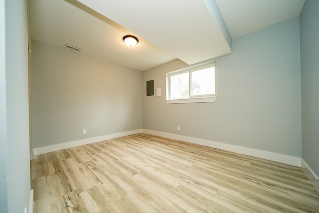 unfurnished room featuring baseboards, electric panel, visible vents, and wood finished floors