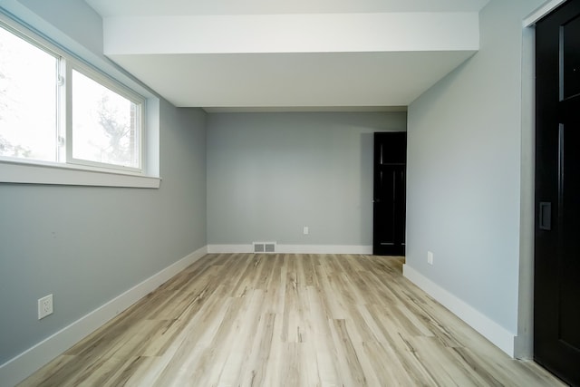 spare room featuring light wood-type flooring, baseboards, and visible vents