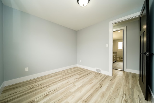 unfurnished room with visible vents, light wood-style flooring, and baseboards