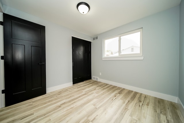 unfurnished bedroom featuring baseboards, visible vents, light wood-style flooring, and a closet