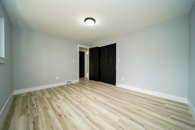 unfurnished bedroom with light wood finished floors, baseboards, and visible vents