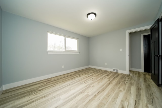 unfurnished room with light wood finished floors, baseboards, and visible vents