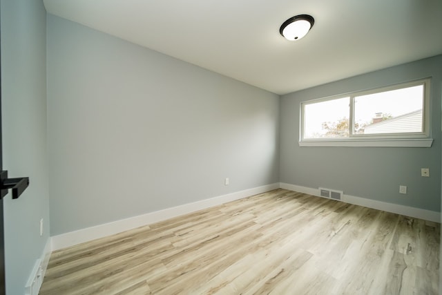 empty room featuring light wood finished floors, baseboards, and visible vents