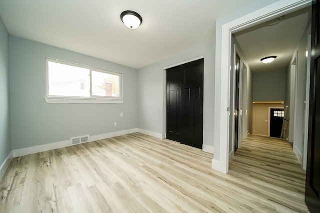 unfurnished bedroom featuring light wood-style floors, a closet, visible vents, and baseboards