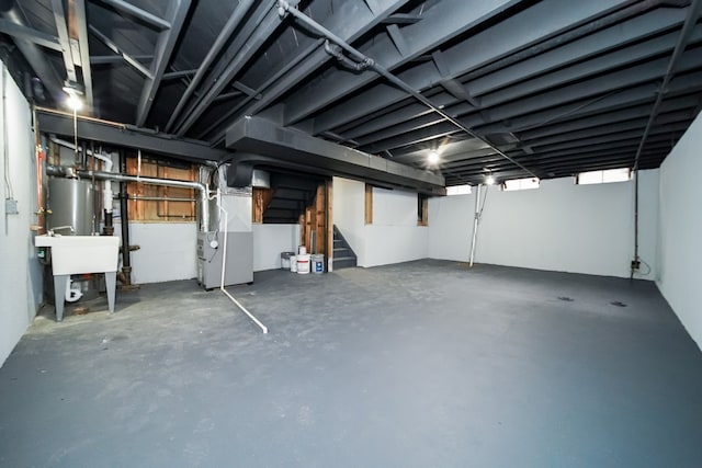 below grade area featuring water heater, a sink, stairway, and heating unit