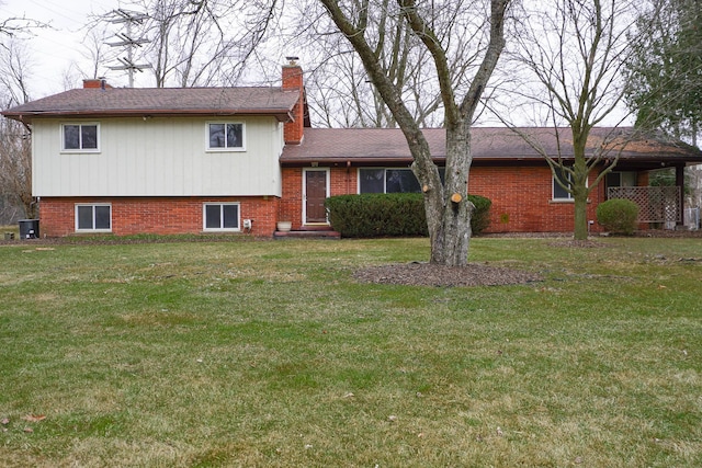 split level home featuring central AC, brick siding, a chimney, and a front lawn