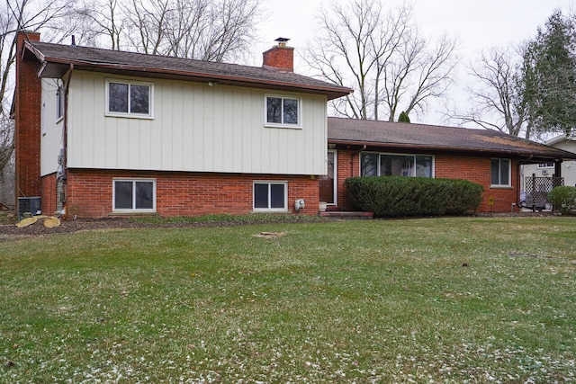 view of front of property featuring a chimney, central AC unit, a front lawn, and brick siding