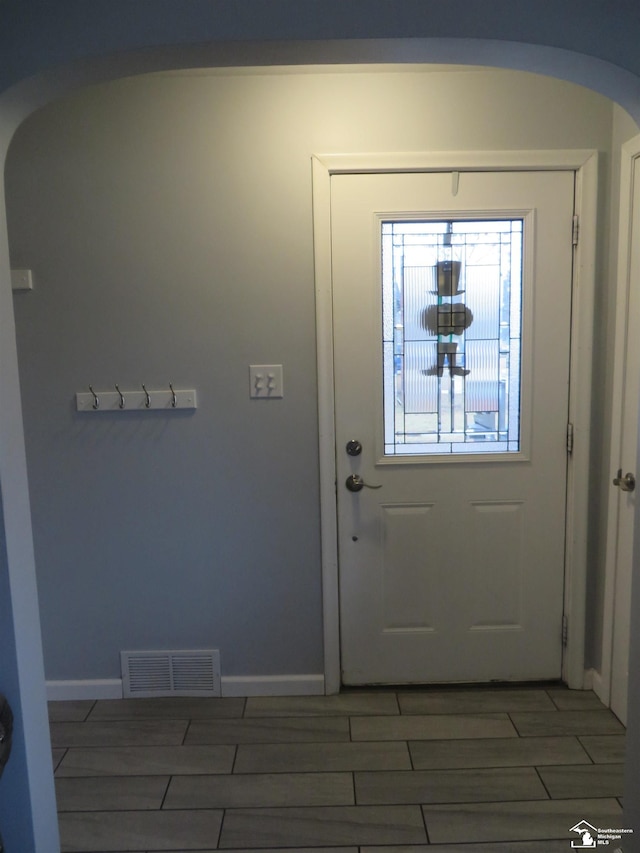 entryway with arched walkways, baseboards, visible vents, and wood tiled floor