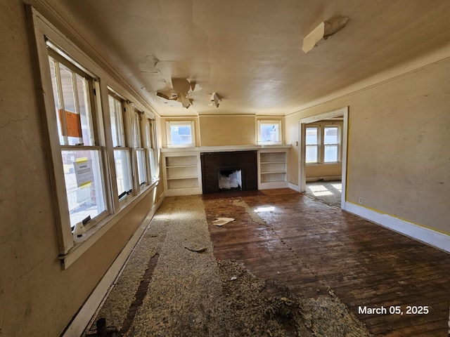 unfurnished living room featuring hardwood / wood-style flooring, a fireplace with flush hearth, and baseboards