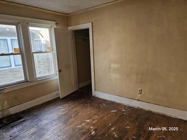 unfurnished room featuring ornamental molding, dark wood finished floors, a textured ceiling, and baseboards