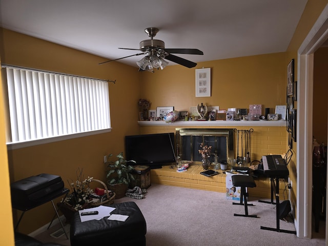 living area featuring carpet, ceiling fan, and a brick fireplace