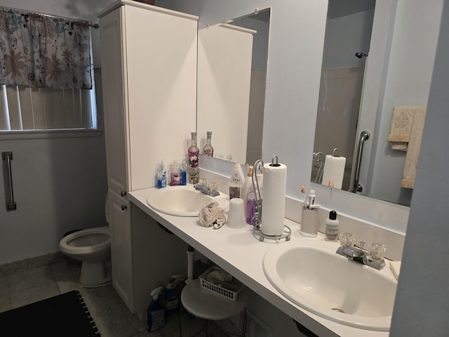 bathroom with double vanity, a sink, toilet, and tile patterned floors