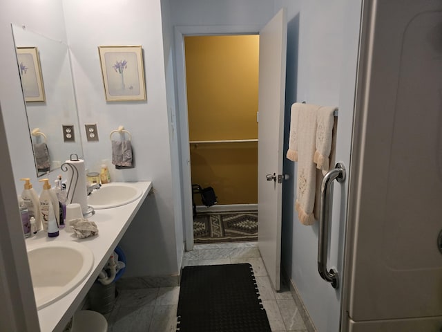 full bathroom with double vanity, baseboards, and a sink