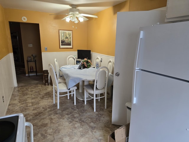 dining room with a ceiling fan and wainscoting