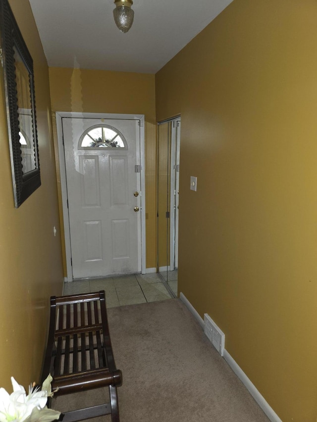 doorway to outside with baseboards, carpet flooring, visible vents, and tile patterned floors