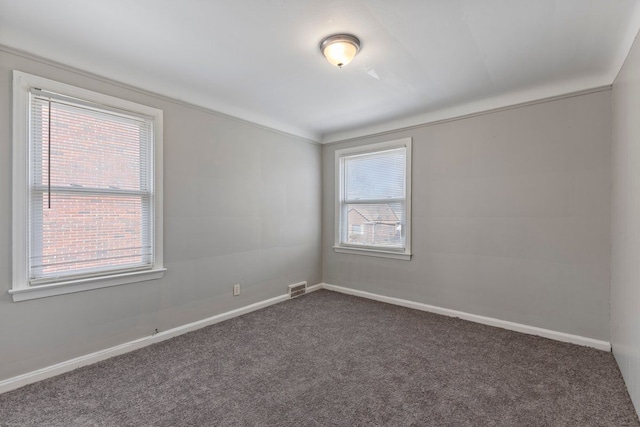 unfurnished room featuring visible vents, baseboards, and dark carpet