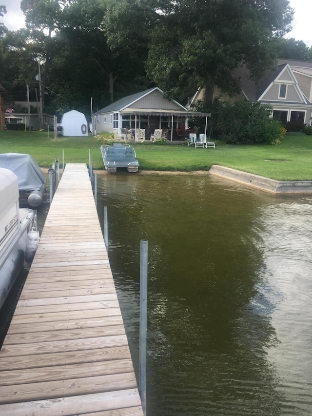 dock area with a water view and a yard