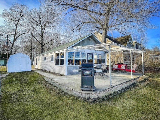 rear view of property with board and batten siding, a yard, a patio area, a storage unit, and an outbuilding