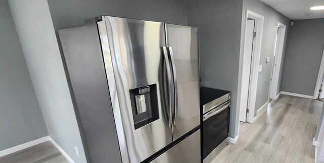 kitchen featuring stainless steel appliances, light wood-style flooring, and baseboards