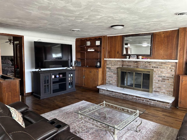 living room with wood finished floors, a fireplace, visible vents, and a textured ceiling