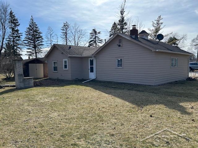 back of house with a storage unit, a yard, and an outdoor structure