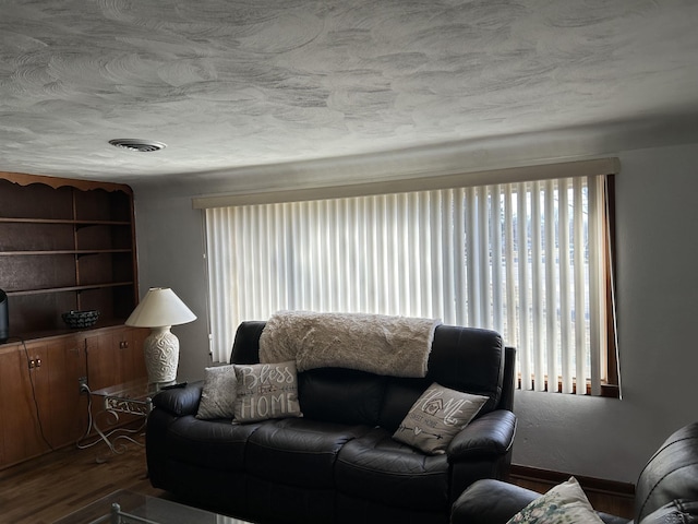 living room with dark wood-style floors, visible vents, and a textured ceiling