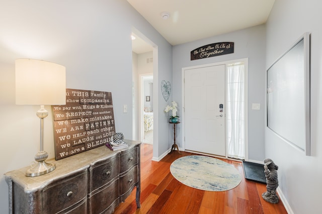 foyer featuring visible vents, wood finished floors, and baseboards