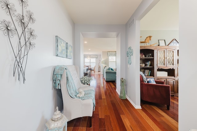 corridor featuring visible vents, baseboards, and hardwood / wood-style floors