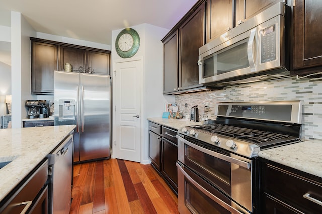 kitchen featuring light stone counters, stainless steel appliances, and dark wood-style flooring