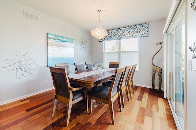 dining area featuring visible vents, an inviting chandelier, light wood-type flooring, and baseboards