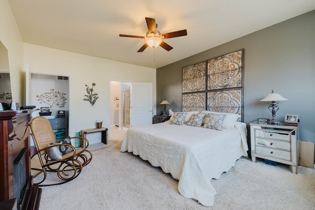 carpeted bedroom with ensuite bathroom and a ceiling fan