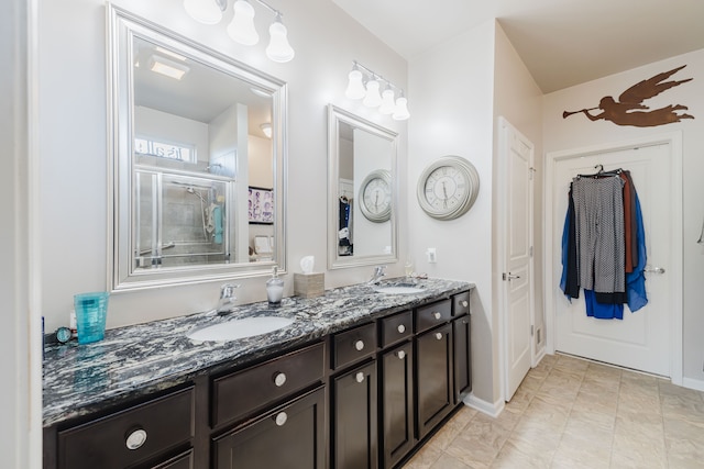 full bathroom featuring double vanity, an enclosed shower, baseboards, and a sink