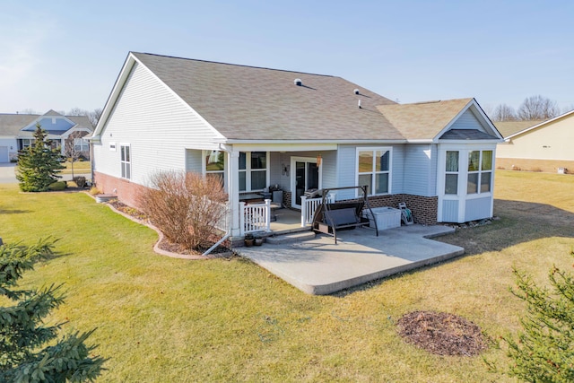 rear view of property featuring a patio, brick siding, roof with shingles, and a lawn